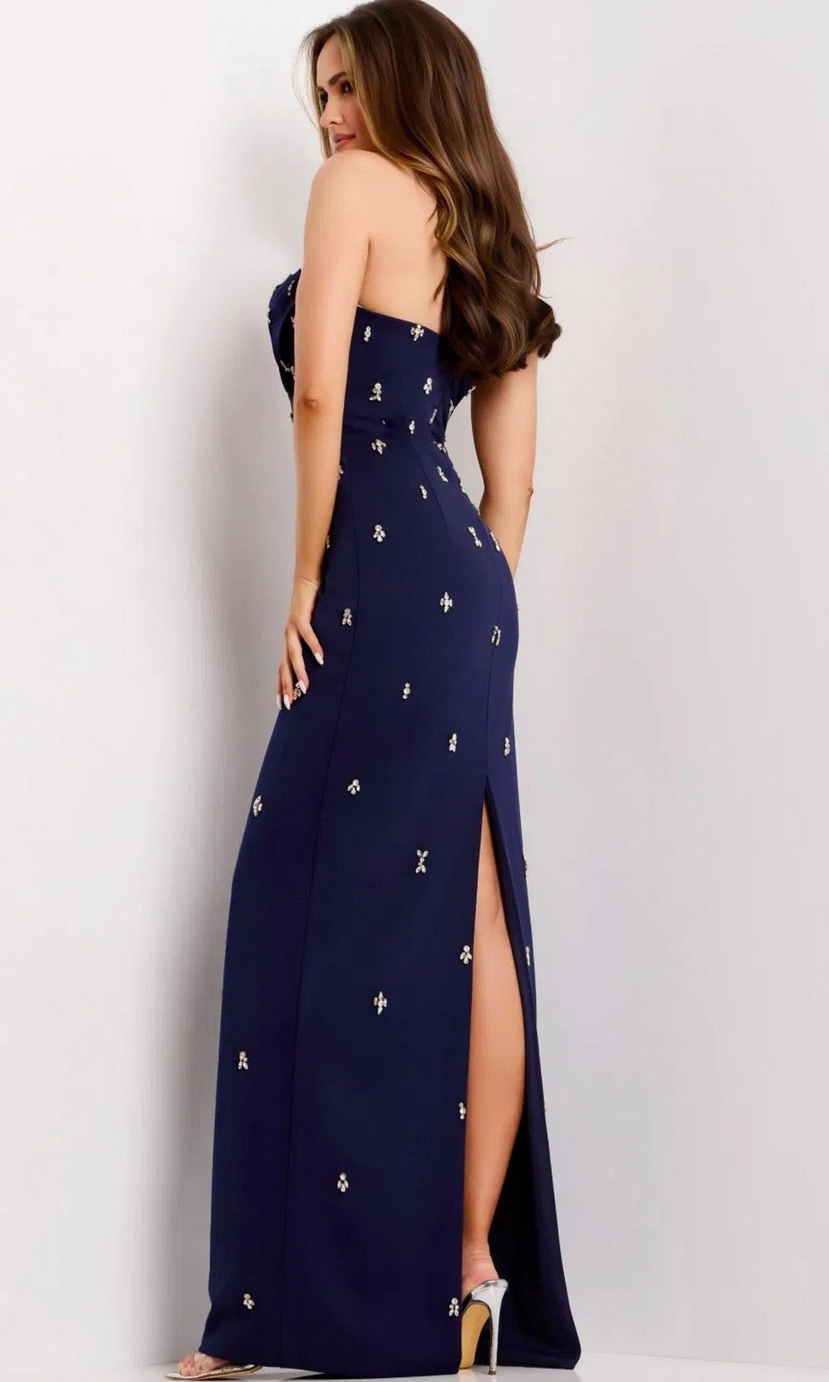 A woman in profile wears the Jovani 43824 Long Prom Dress, a sleeveless navy blue maxi with a side slit and crystal-beaded appliques for embellishment.